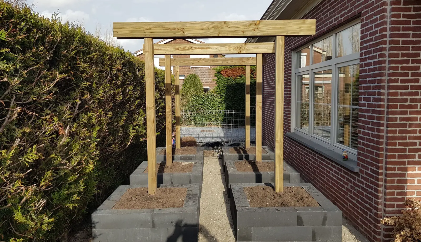 Aanleg van een tuin met houten pergola en plantenbakken